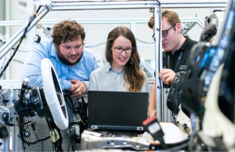 Three students working on a laptop